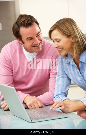 Mature couple using laptop in domestic kitchen Stock Photo