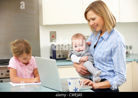 Mother with children using laptop in kitchen Stock Photo