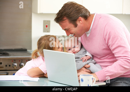 Father with children using laptop in kitchen Stock Photo