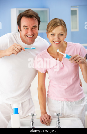 Couple cleaning teeth together in bathroom Stock Photo