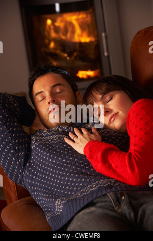 Middle Aged Couple Cuddling On Sofa By Cosy Log Fire