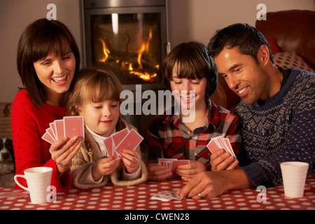 Portrait Of Family Playing Cards By Cosy Log Fire Stock Photo