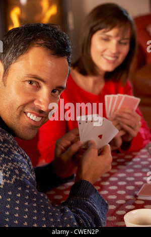 Couple Playing Cards By Cosy Log Fire Stock Photo