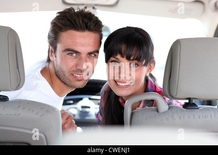 Couple looking over their shoulders in a car Stock Photo