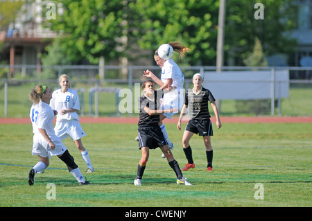 Soccer players rises above the crowd to complete a header during a high school match. Stock Photo