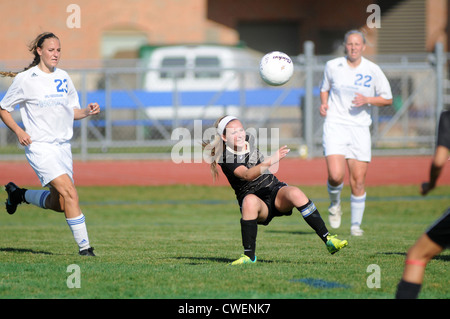 Soccer player recoils toward the turf following a scissors kick effort during a high school match. USA. Stock Photo