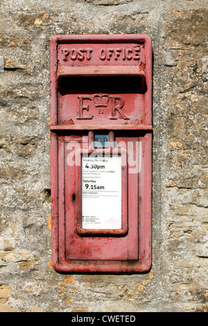 Old faded red ER British Post Box set into stone wall Oxfordshire England UK Stock Photo