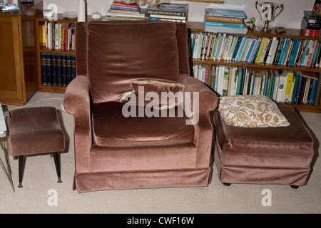 An armchair with footstools and cushions provide comfort in a domestic lounge Stock Photo