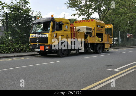 Yellow line painting vehicle with fire going on truck bed to heat material Stock Photo