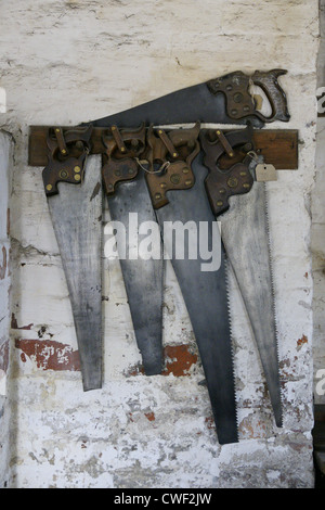 Old hand carpenters hand saws hanging on a rack Stock Photo