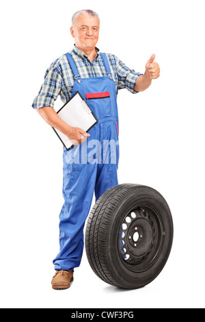 Full length portrait of a mature mechanic with tyre isolated on white background Stock Photo