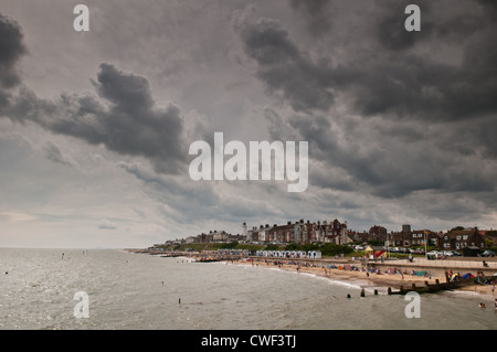 View from the pier of large thunderous dramatic clouds over Southwold on a summer day with holidaymakers on the beach Stock Photo