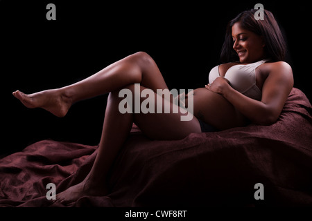 Young beautiful pregnant indian woman touching her belly Stock Photo