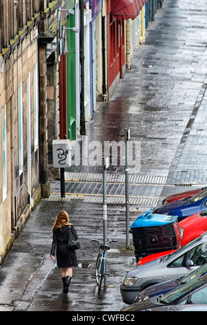 Young woman walking along a wet and deserted street, Edinburgh, Scotland Stock Photo