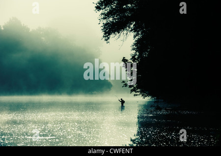 A man fishing in the early morning mist of the Dordogne river, Dordogne, Aquitaine, France Stock Photo