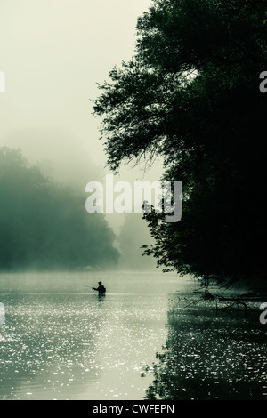 A man fishing in the early morning mist of the Dordogne river, Dordogne, Aquitaine, France Stock Photo