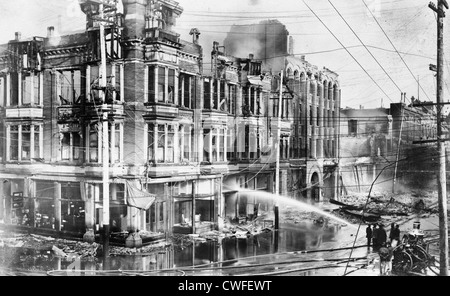 Block of burned buildings in San Francisco after the 1906 earthquake with fire truck spraying water on them Stock Photo