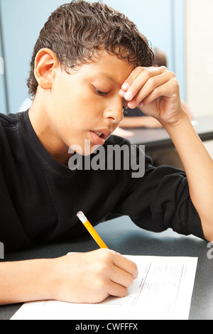 Handsome school boy struggling to finish a test in class. Stock Photo
