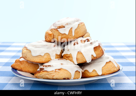 A plate of delicious cinnamon rolls coated with sugary frosting glaze. Stock Photo