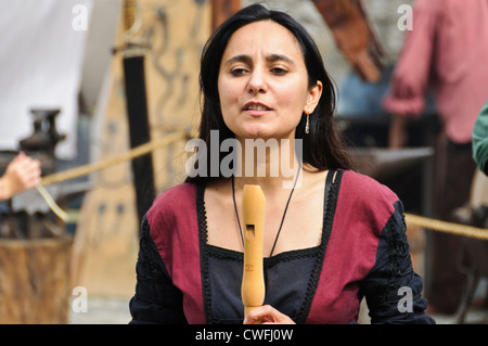 Female flutist with black hair in historic clothing, fipple flute recorder, medieval market historical Staufer town Bad Wimpfen Stock Photo