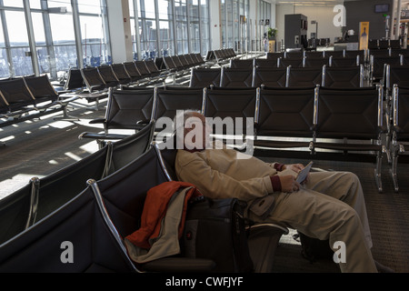 Man asleep in empty seating area of departure lounge at Dulles airport Washington DC USA Stock Photo