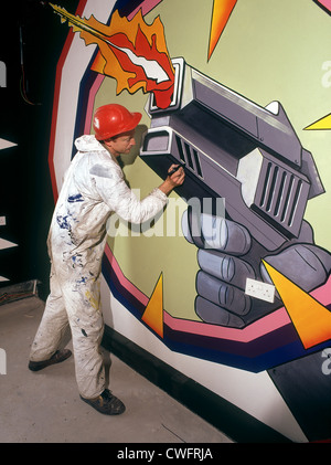 Specialist painter putting the final touches to a mural in a theme park. Stock Photo