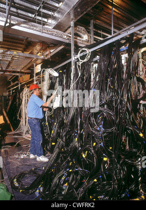 Electrical services engineer working on cabling in commercial offices. Stock Photo