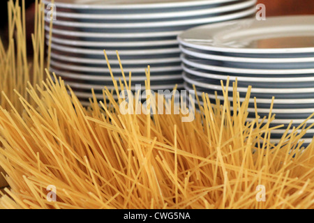 Pasta and stacks of plates in restaurant, food background. Stock Photo