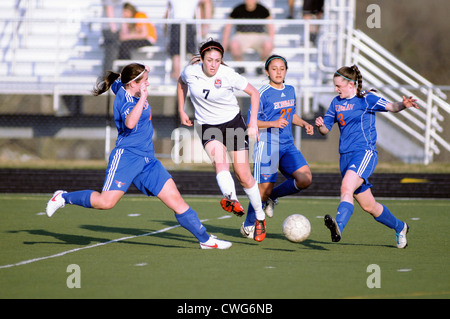 Soccer Three defending players converge on the ball during a high school match. Stock Photo