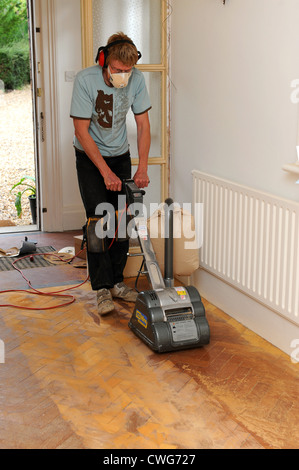 Man using floor sander on solid wooden parquet flooring Stock Photo