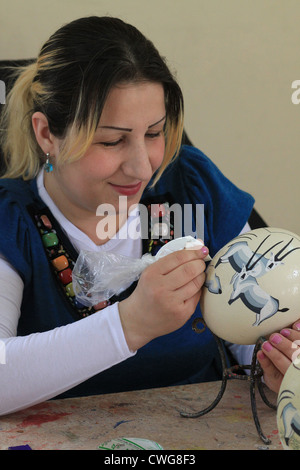 A woman painting an ostrich egg in the Azraq Lodge, where women from the local community are employed to support them. Jordan. Stock Photo