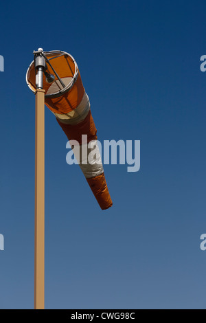 Vertical image of orange and white windsock isolated to top third of the pole Stock Photo