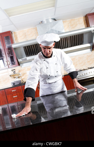 young male professional chef cleaning in commercial kitchen Stock Photo