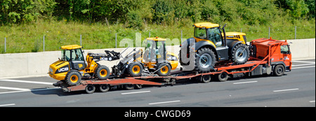 Three new JCB machines being transported on low loader Stock Photo