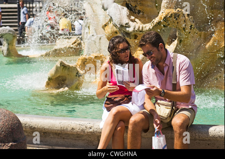 Rome, Italy - August 2012 - Couple looking at map sitting on a fountain Stock Photo