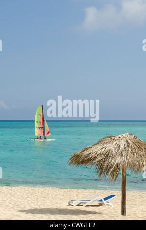 Beach chair, umbrella and sailboat at Sol Cayo Santa Maria Resort, Cayo Santa Maria, Cuba. Stock Photo