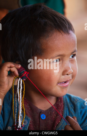 A child from the ANN TRIBE plays with bead work in a village near KENGTUNG or KYAINGTONG - MYANMAR Stock Photo