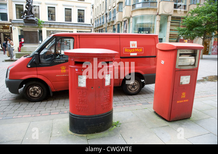 red royal mail van parked behind a double letter box and a franked mailbox in manchester city centre Stock Photo