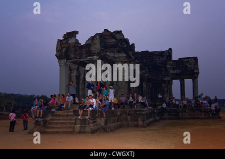 Horizontal view of tourists gathered on one of the ruins to watch the sunrise rise over Prasat Angkor Wat. Stock Photo