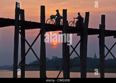 The BURMESE use the teak U BEINS BRIDGE to commute across the Taungthaman Lake at sunrise - AMARAPURA, MYANMAR Stock Photo
