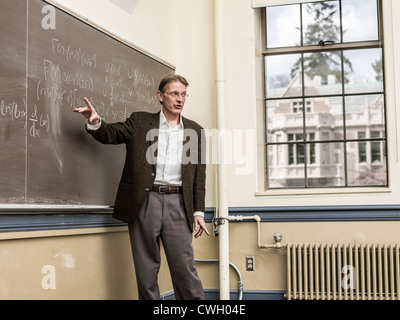 Caucasian teacher writing on blackboard Stock Photo