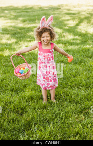 Mixed race girl holding basket of Easter eggs Stock Photo