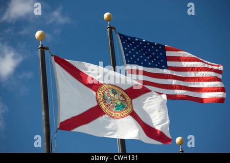 FLORIDA STATE FLAG UNITED STATES FLAG FLYING ON FLAGPOLES ON BLUE SKY BACKGROUND Stock Photo