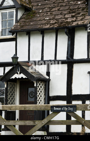 Beware of the Dog sign on a gate in front of an old black and white timber framed house. Herefordshire. England Stock Photo