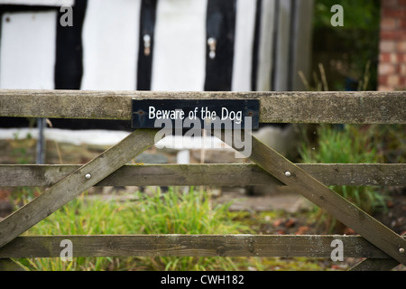 Beware of the Dog sign on a gate in front of an old black and white timber framed house. Herefordshire. England Stock Photo