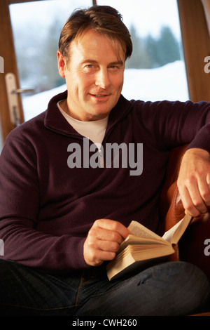 Middle Aged Man Relaxing With Book Sitting On Sofa Stock Photo