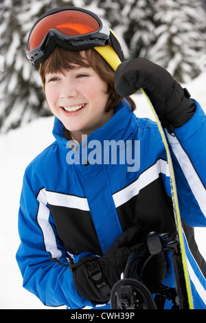 Young Boy With Snowboard On Ski Holiday In Mountains Stock Photo