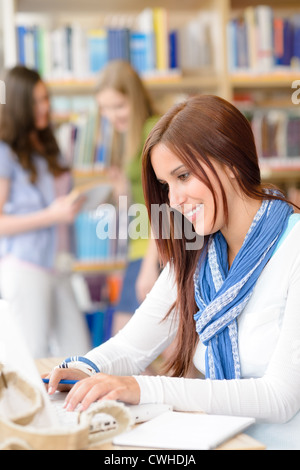 Female brunette student at high school library working on laptop Stock Photo