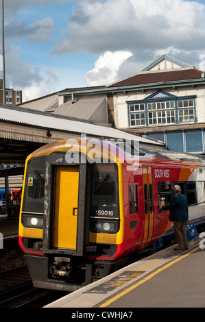 Passenger waiting to board a class 159 passenger train in South West Trains livery at Clapham Junction railway station, England. Stock Photo