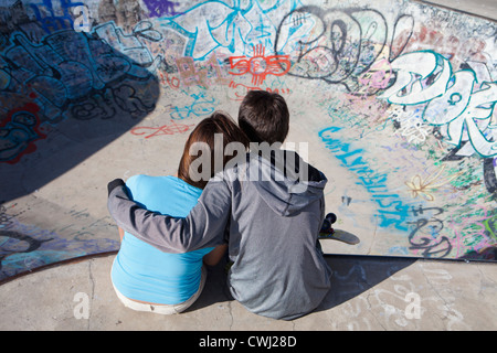 Boy and girl hugging in skateboard park Stock Photo